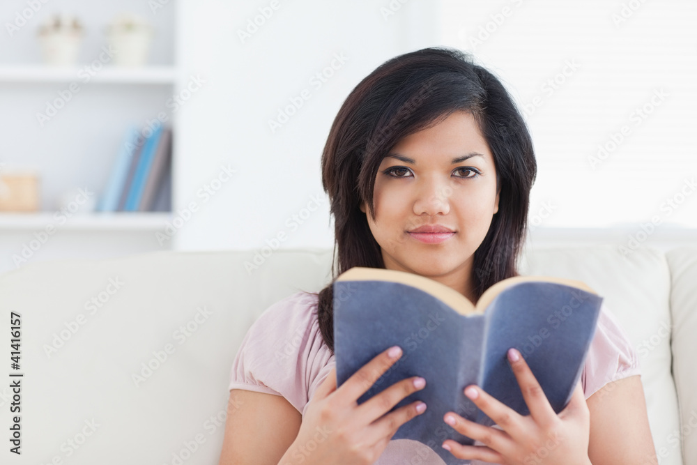 Woman sitting on a couch and holding a book