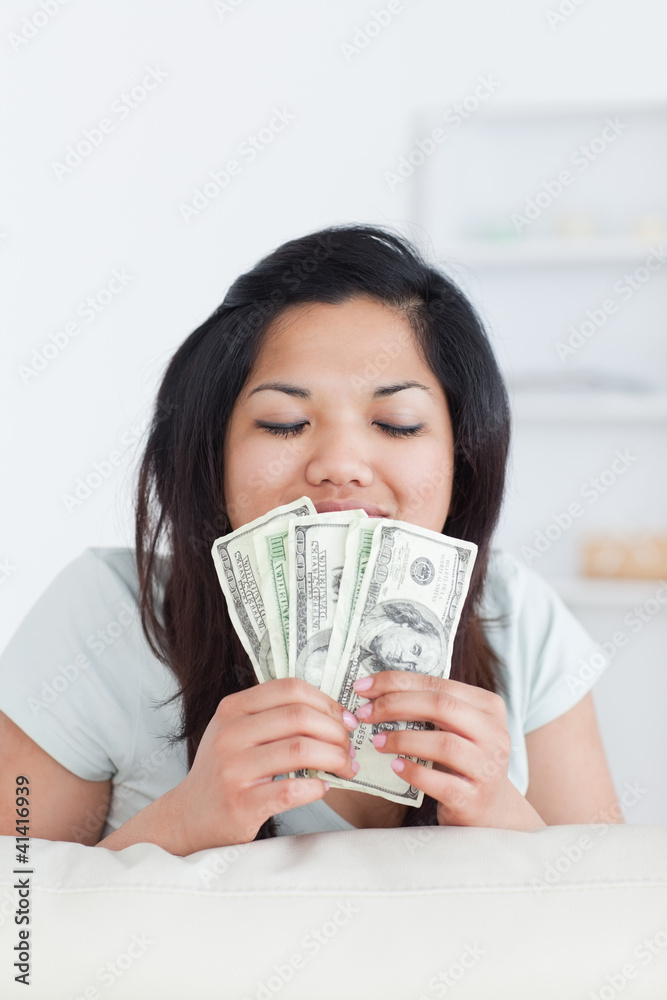 Woman closing her eyes as she holds some dollar bills Woman closing her eyes as she holds some dollar bills