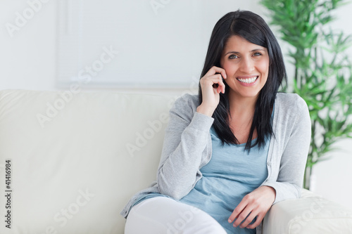 Woman talking on the phone while resting on a sofa