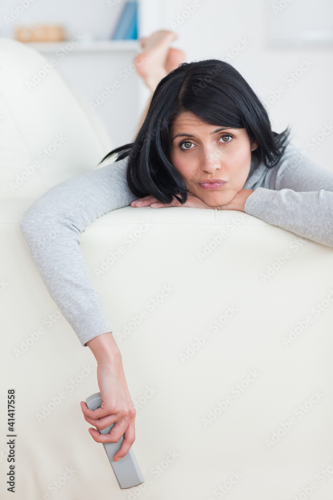 Sad woman on a sofa holding a television remote Sad woman on a sofa holding a television remote