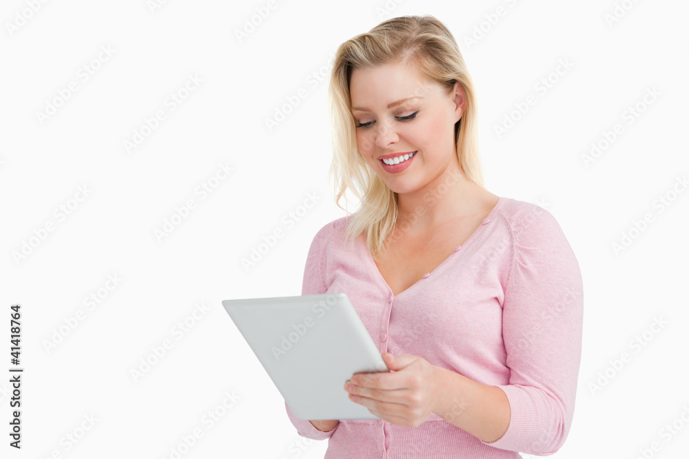 Blonde woman standing while using her touchscreen Blonde woman standing while using her touchscreen