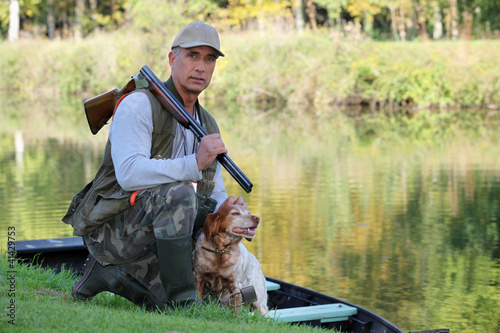 Photographie Un chasseur et son chien près d&#39;une rivière.