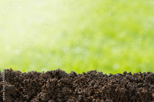 Pile of soil against green defocused background with copy space