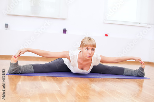 Woman doing stretching yoga exercise at sport gym