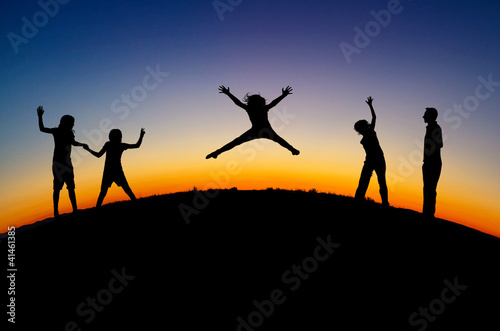 silhouette of teens on hill in sunset