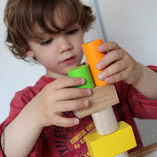 enfant qui empile des formes en bois