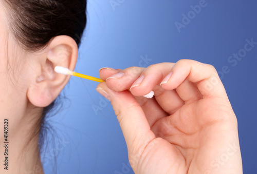 Human ear and cotton swabs close-up on blue background
