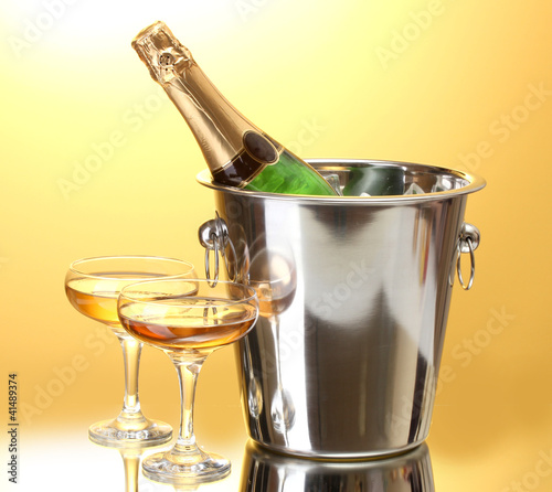 Champagne bottle in bucket with ice and glasses of champagne,