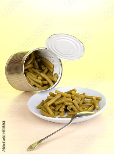 Open tin can and plate with french bean and spoon