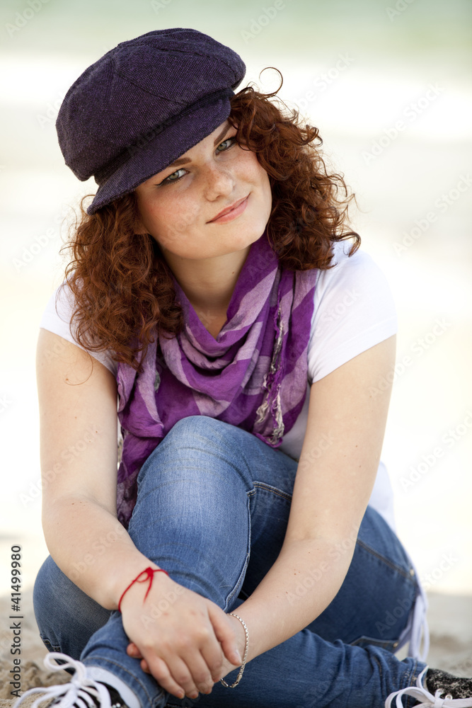 Funny teen girl sitting on the sand at the beach.