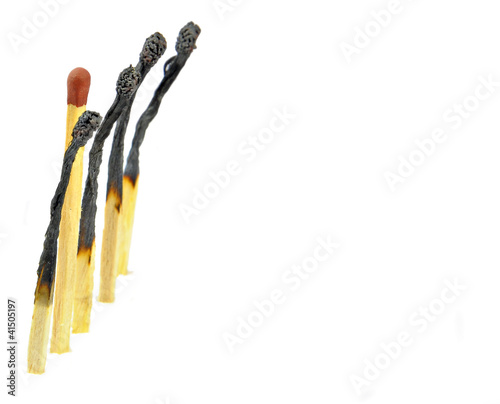 row of burnt match sticks with one unburnt stick in the middle