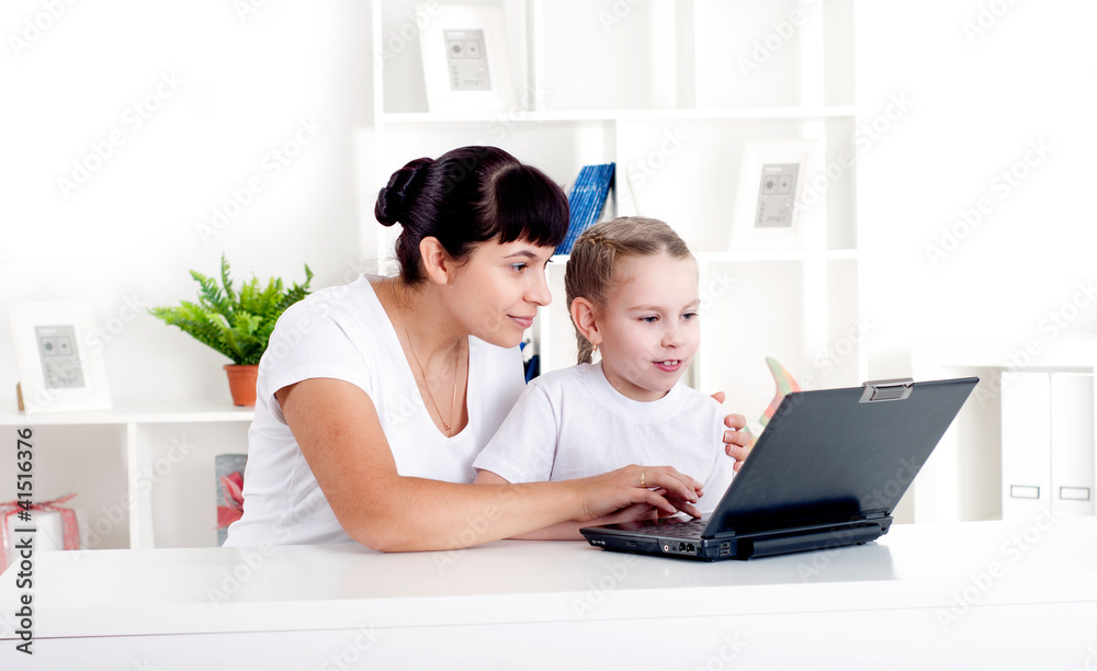 Mom and daughter are working together for a laptop Mom and daughter are working together for a laptop