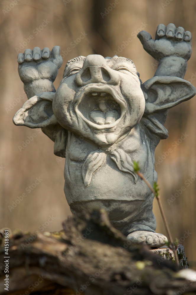 clay figure with hands up standing on a trunk