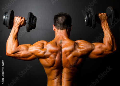 rear view of bodybuilder training with dumbbells