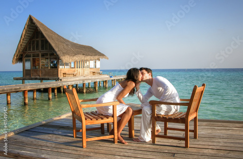 Happy love couple sitting on a jetty at the beach (maldives) © XtravaganT