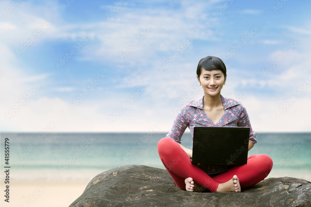 Beautiful woman with laptop at the beach