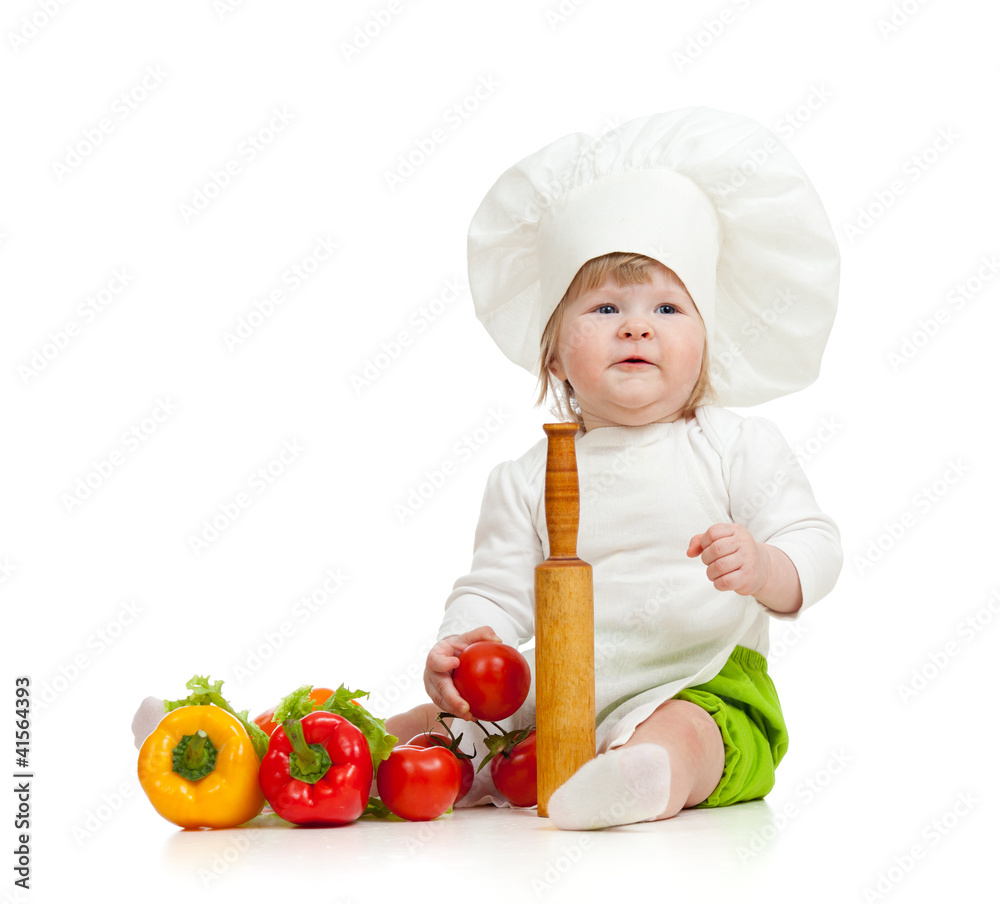 Kid in chef hat with healthy food vegetables Kid in chef hat with healthy food vegetables