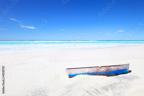 Old boat on white tropical sunny beach and a blue sky