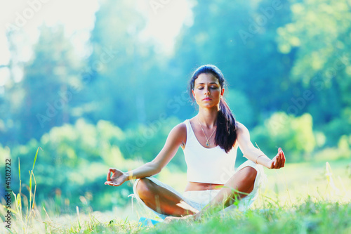 Young woman doing yoga exercise in green park photo