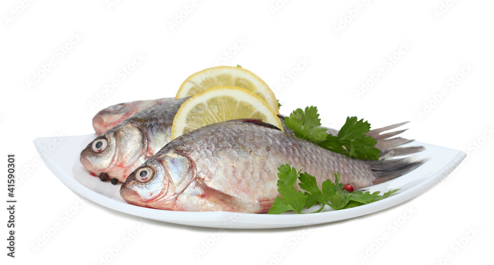 Fresh fishes with lemon and parsley on plate isolated on white Fresh fishes with lemon and parsley on plate isolated on white