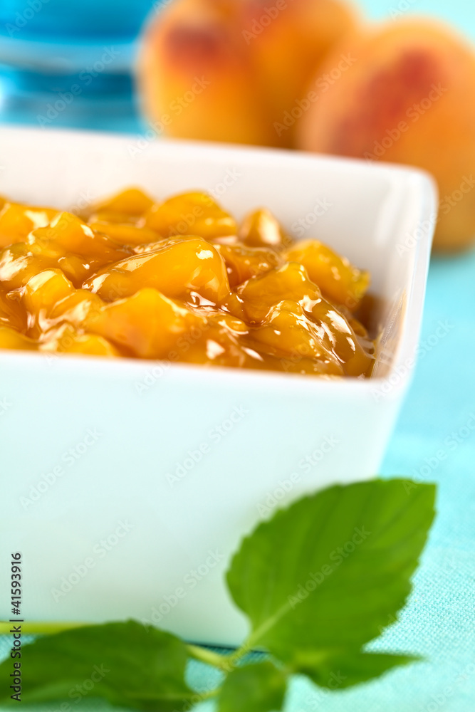Fresh peach compote in bowl with mint leaf in the front Fresh peach compote in bowl with mint leaf in the front