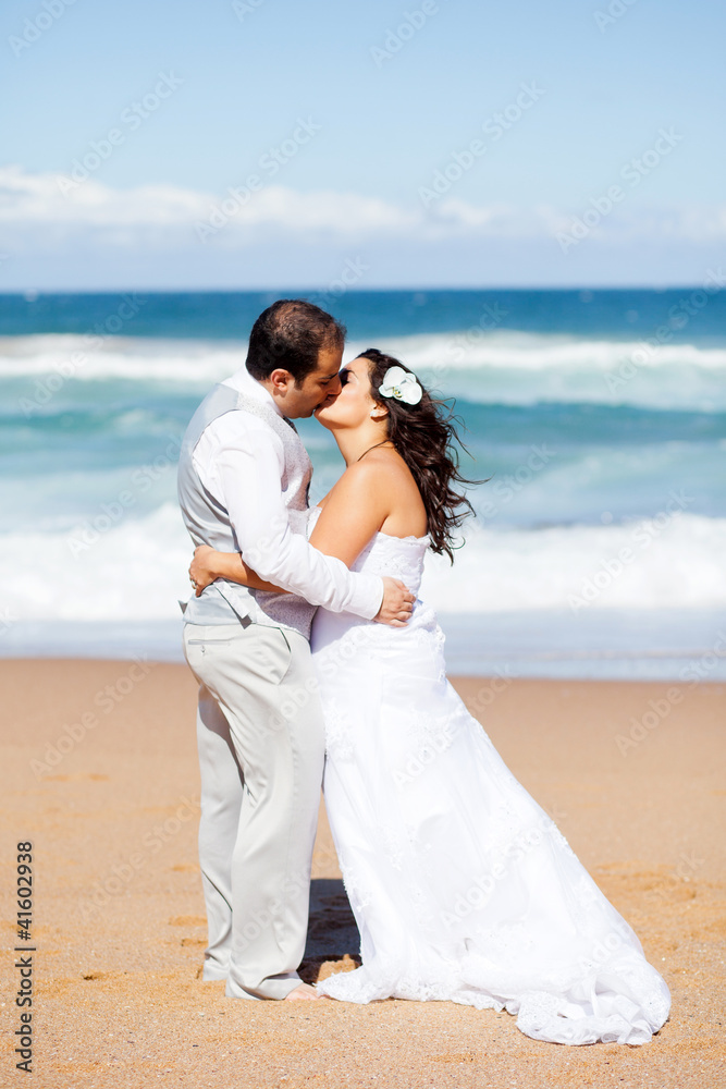 newlywed couple kissing on beach