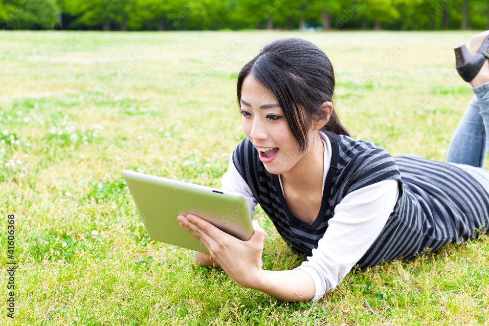 Fototapeta premium attractive asian woman using tablet computer in the park