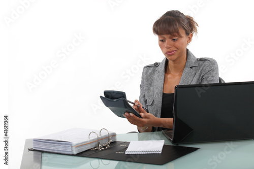 Businesswoman using a calculator at her desk