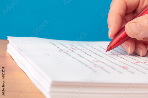 Hand with Red Pen Proofreading a Manuscript Closeup