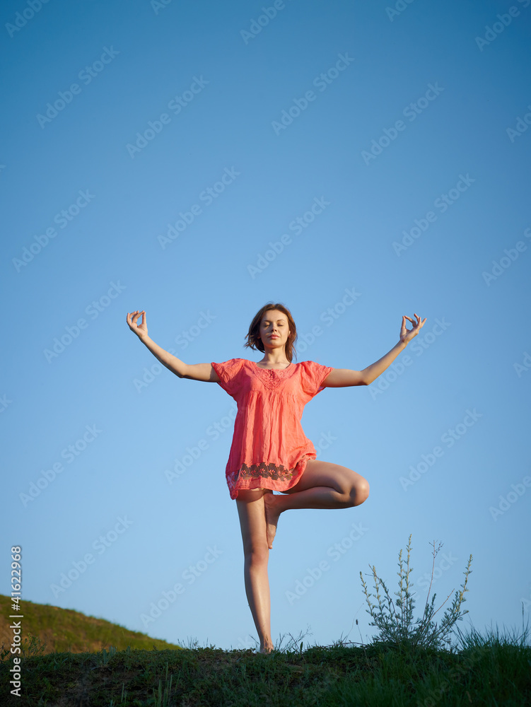 The young woman in an orange dress, costs on a green hill The young woman in an orange dress, costs on a green hill