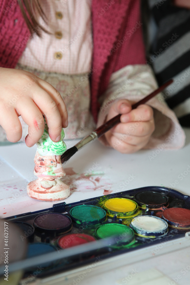 Child painting a plaster figurine Child painting a plaster figurine