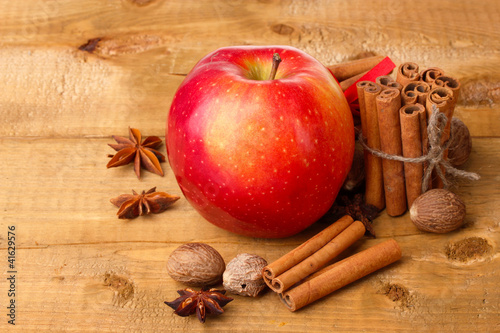 Cinnamon sticks,red apple, nutmeg,and anise on wooden table