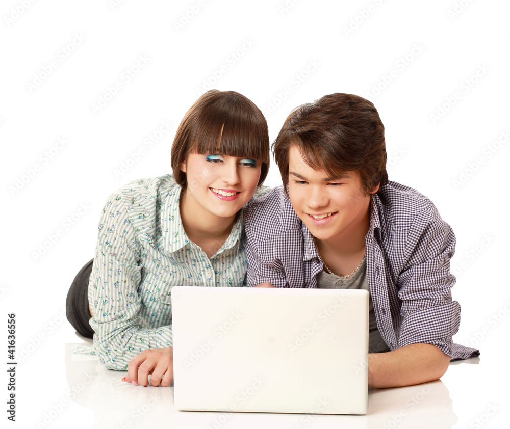 A couple lying on the floor behind a laptop, isolated on white A couple lying on the floor behind a laptop, isolated on white