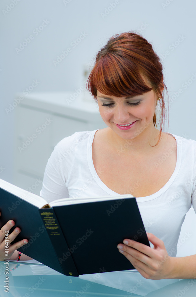 Fototapeta premium rothaarige junge frau liest in einem buch