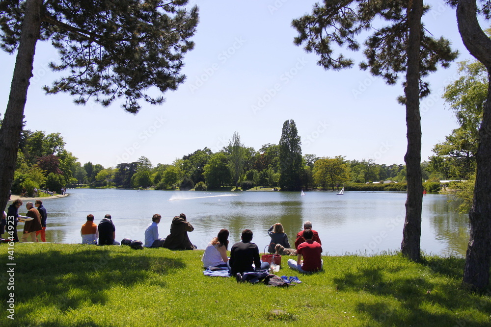 Fototapeta premium Parisiens sur une pelouse devant un lac du Bois de Boulogne à Paris