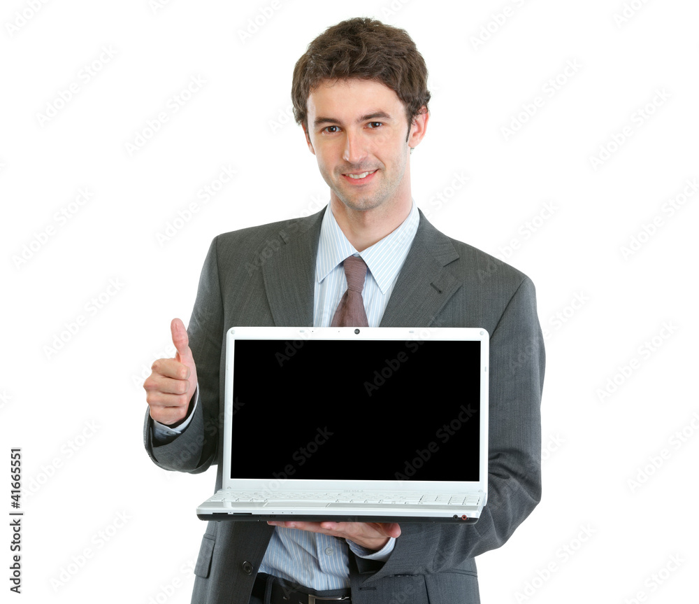 Modern businessman showing laptops blank screen and thumbs up Modern businessman showing laptops blank screen and thumbs up