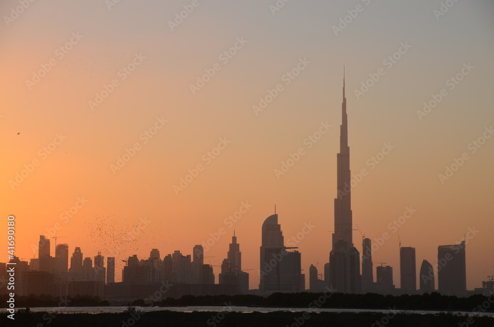 Silhouette of Burj Khalifa building and Dubai skyline at sunset