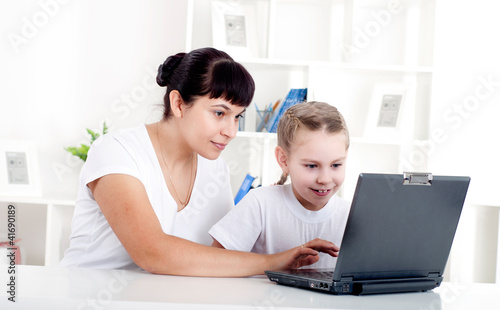 Mom and daughter are working together for a laptop