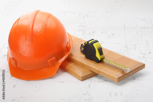 An orange hardhat with a ruler on wooden planks