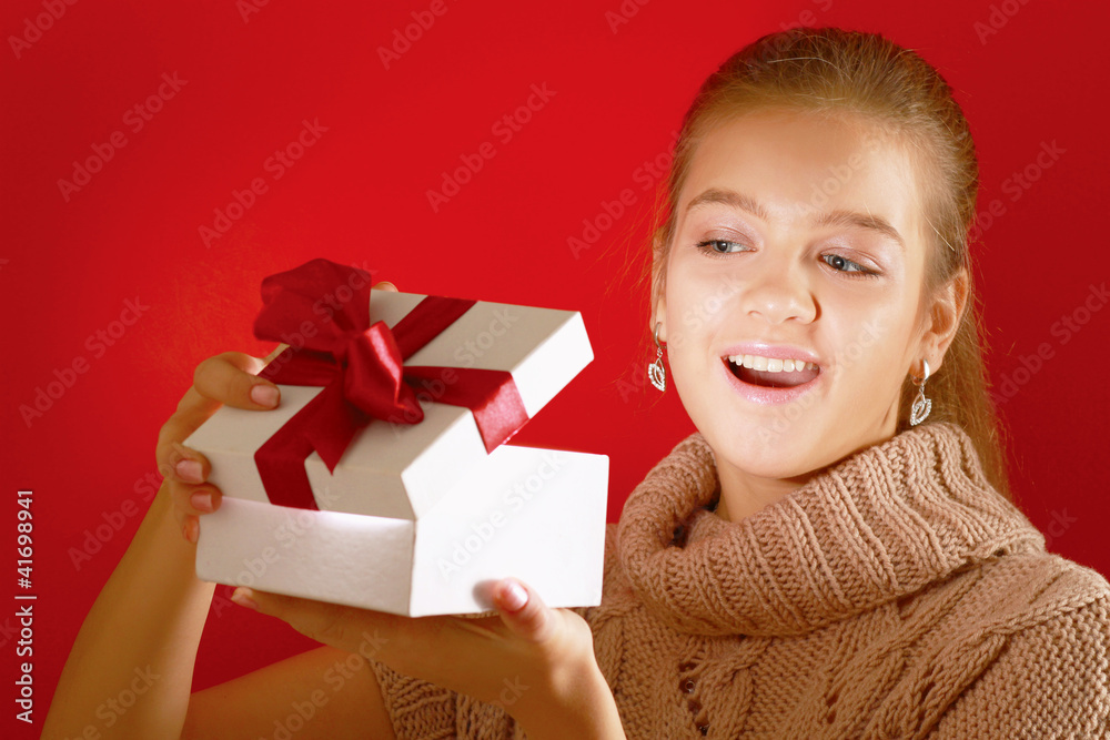 Happy girl opening gift box isolated on red background Happy girl opening gift box isolated on red background