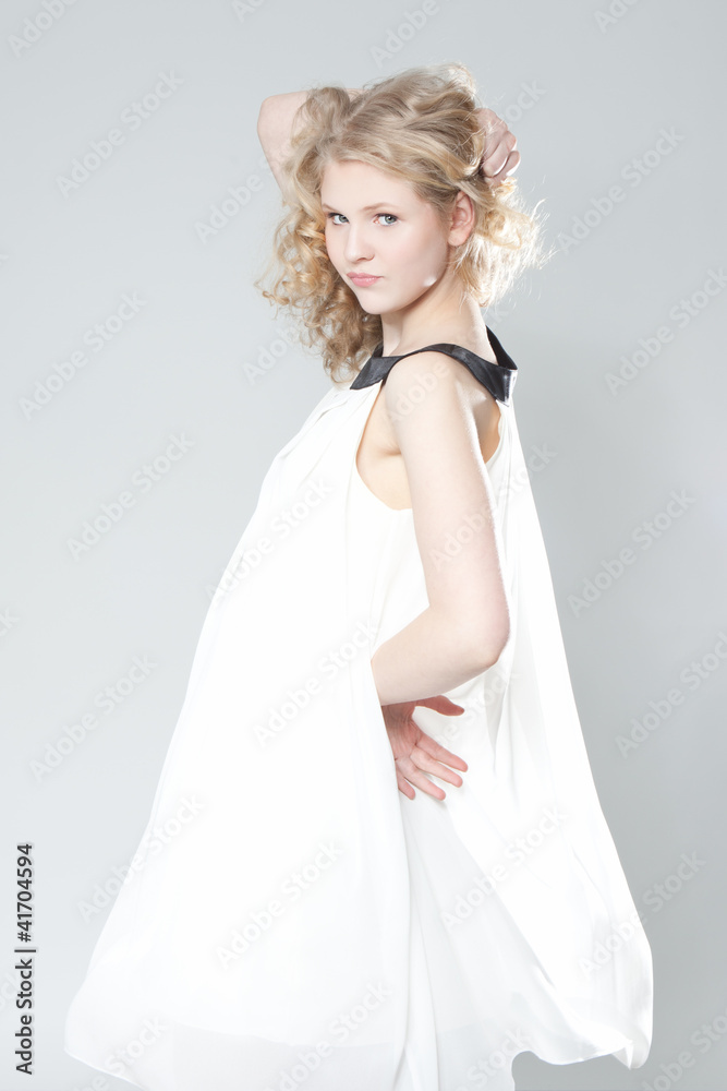 Young blonde girl posing in studio in white dress Young blonde girl posing in studio in white dress