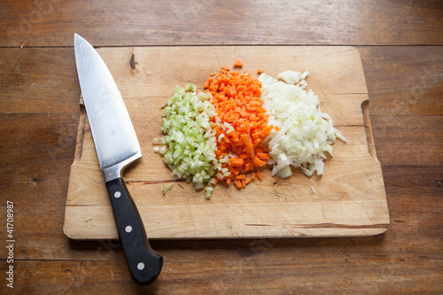soffritto di sedano, carota e cipolla sul tagliere con coltello photo