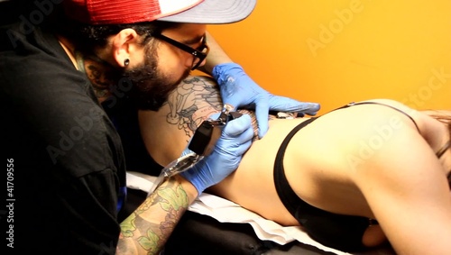 tatuador realizando tatuaje a chica