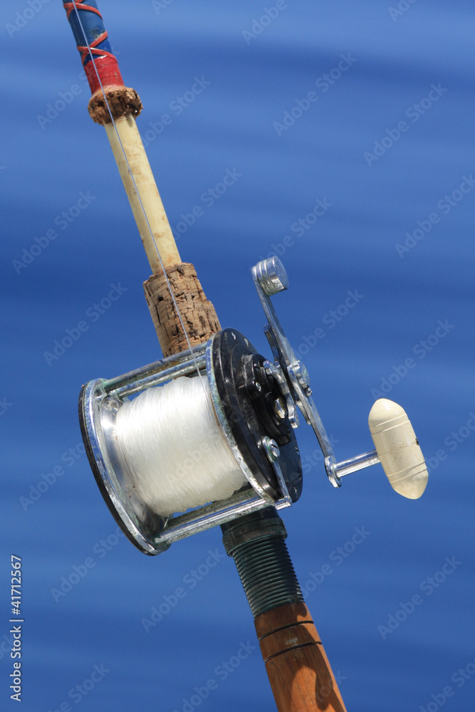 Old fishing reel with blue water background Old fishing reel with blue water background
