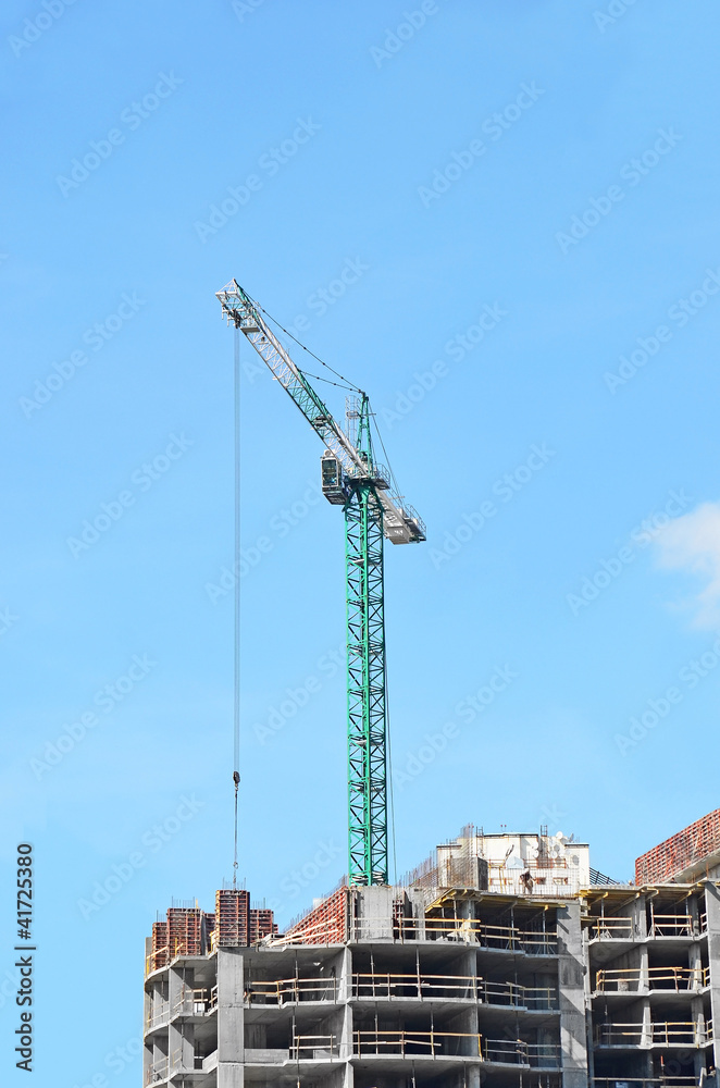 Building crane and building under construction against blue sky Building crane and building under construction against blue sky