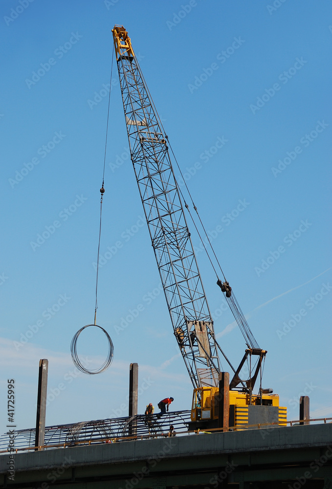 Iron workers moving rebar rings using a large crane