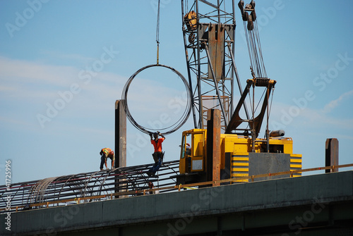 Iron workers moving rebar rings using a large crane i