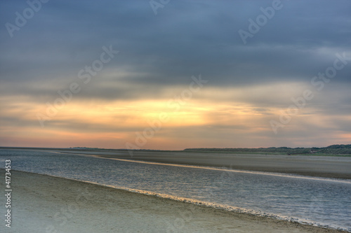 Canvas Print Sunrise above a beach and a creek at ebb tide