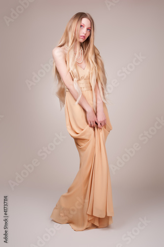 Beautiful young woman wearing a sexy beige evening dress