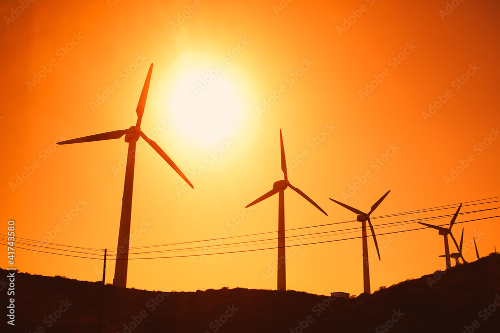 Wind turbines farm silhouettes on sun background Wind turbines farm silhouettes on sun background